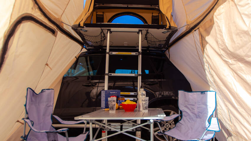 Intérieur de la TrïUp Legend avec annexe, table de camping et couchage 3 places, prêt pour un bivouac tout confort
